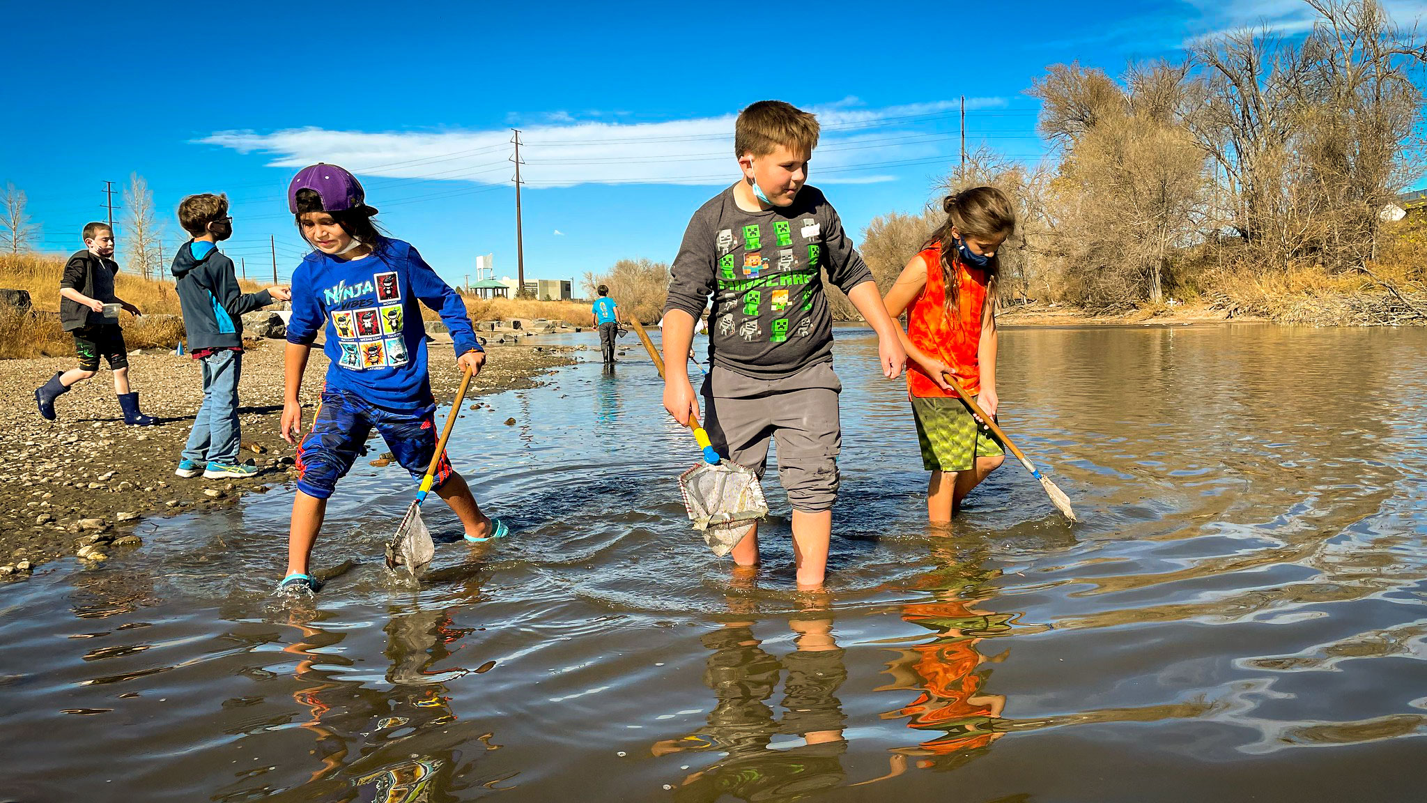 Kids wade through the South Platte River with nets during SPREE Summer Camp