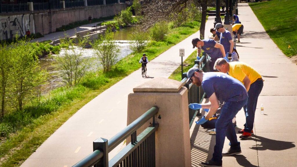 Volunteers refresh paint on railings along the Cherry Creek for Greenway's Fall Stewardship Day
