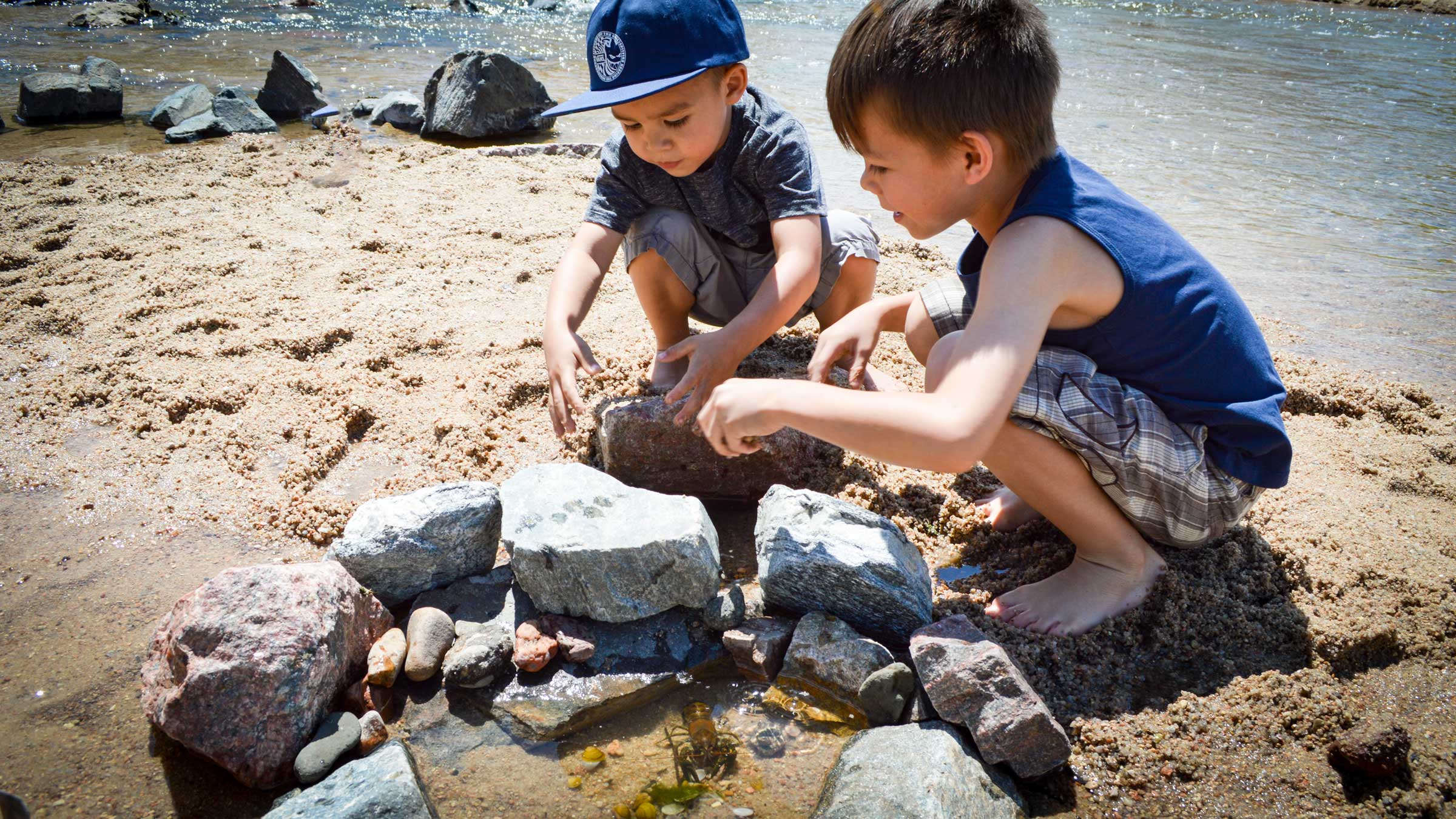 Children build a pool to house crawfish along the South Platte River at Art on the River