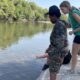 students testing water temperature at the river